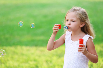 Cute girl blowing soap bubbles