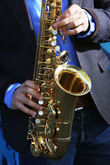 Saxophonist plays jazz on the street, close up