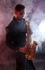 Fototapeta na wymiar Young man professionally plays sax in red smoke