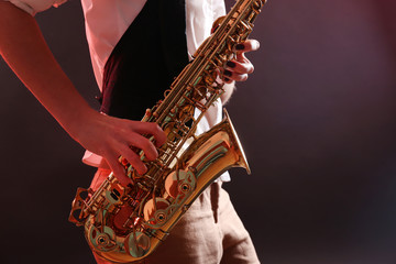 Obraz premium Saxophone in female hands on dark background, close up