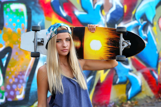 Young woman with skating board  on painted wall background