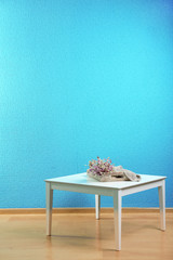 Little table with flowers on blue wall background