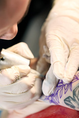 Obraz na płótnie Canvas Professional tattoo artist doing tattoo on client hand