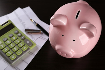 Pig moneybox and calculating equipment on desk closeup