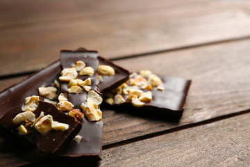 Chocolate pieces with nuts on color wooden background
