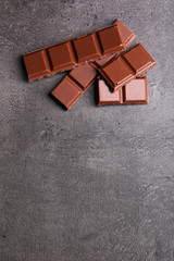 Milk chocolate pieces on gray background