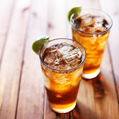 iced tea with lime wedges on wooden table and copy space composition