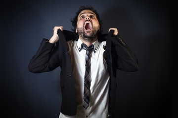 Young man screaming on black background