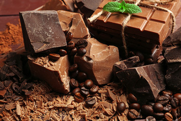 Variety of chocolate pieces, coffee grains and cocoa powder on wooden background