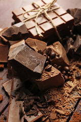 Variety of chocolate pieces, coffee grains and cocoa powder on wooden background