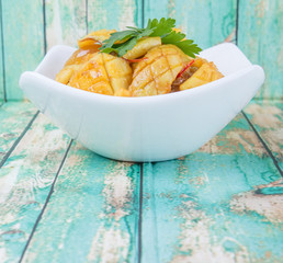 Malaysian dish stir fried squid with parsley leaves in white bowl over wooden background