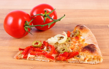 Slice of vegetarian pizza and tomatoes on wooden surface