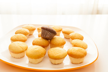 Tasty yellow muffins and chocolate muffin on top