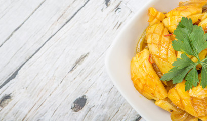 Malaysian dish stir fried squid with parsley leaves in white bowl over wooden background