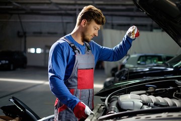 Mechanic checking oil level in a car workshop
