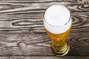 glass of fresh lager beer on a wooden table.