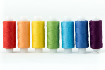 Ряд разноцветных  швейных ниток на катушке.
