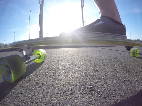 Male foot on the longboard at sunset