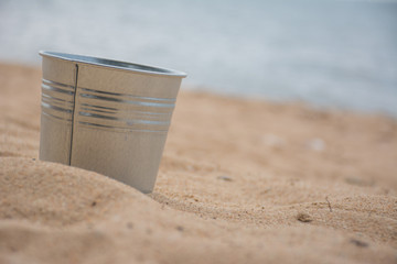 Little aluminium tank on the beach with sea in background