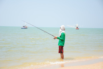 Lone fisherman fishing on the beach in jomtien beach pattaya at
