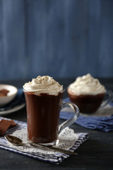 Cups of coffee with cream on color wooden background