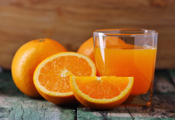 Orange juice glass and fresh oranges on wood
