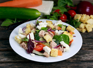 Tuna salad with Spinach, rocket, red ruby chard, tomatoes, cucumbers, white cheese, carrot, red onion, croutons,  on old wooden table background