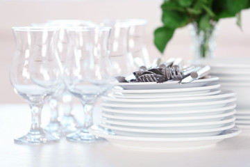 Clean plates, glasses and cutlery on white table
