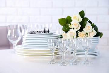 Clean plates, glasses and cutlery on white table