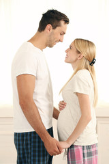 Young pregnant woman with husband in room