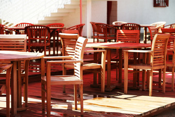 Wooden chairs and tables on summer restaurant terrace