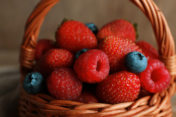 Tasty ripe berries in basket on wooden table close up