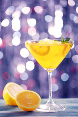 Glass of cocktail with ice on blurred lights background
