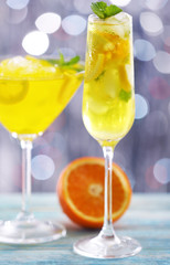 Glasses of cocktails with ice on blurred lights background