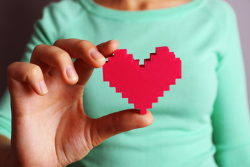 Closeup of plastic puzzle heart in female hand