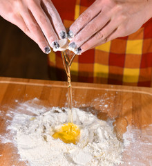 Woman adding egg to the flour