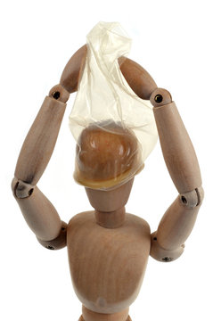 Homme en bois enfilant un préservatif sur sa tête