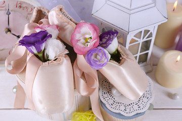 Beautiful composition of ballet shoes, candles, flowers and caskets, close up
