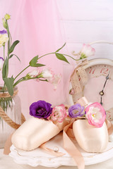 Beautiful composition of decorated ballet shoes on rosy satin background