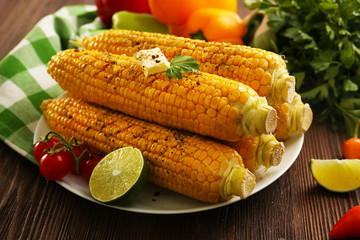 Appetizing grilled corn served with vegetables and green plaid pattern napkin