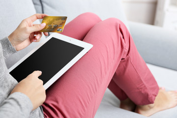 Concept for Internet shopping: woman with digital tablet and credit card sitting on sofa, at home