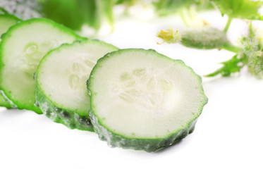 Sliced cucumbers with leafs  on light background, close up