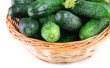 Wicker basket with cucumbers isolated on white