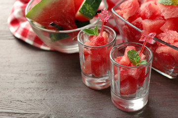 Cold watermelon desserts and drinks in glasses, on wooden table background