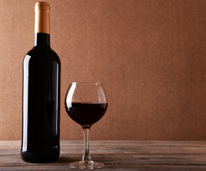 A bottle of red wine and a glass on wooden table