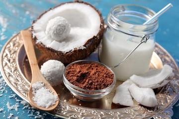 Homemade candies in coconut flakes and ingredients on color wooden background