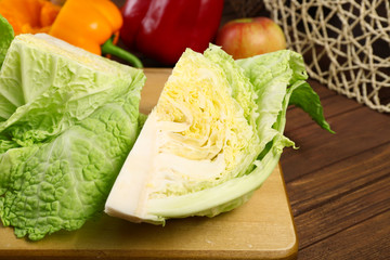 Cut savoy cabbage and pepper on wooden cutting board closeup
