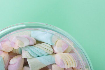 marshmallow candies of different colors in the glass on the background of turquoise. top view. entertainment for children in celebration.