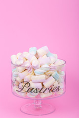 marshmallow candies of different colors in the glass on the background of pink. top view. entertainment for children in celebration.