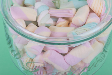 marshmallow candies of different colors in the glass on the background of turquoise. top view. entertainment for children in celebration.